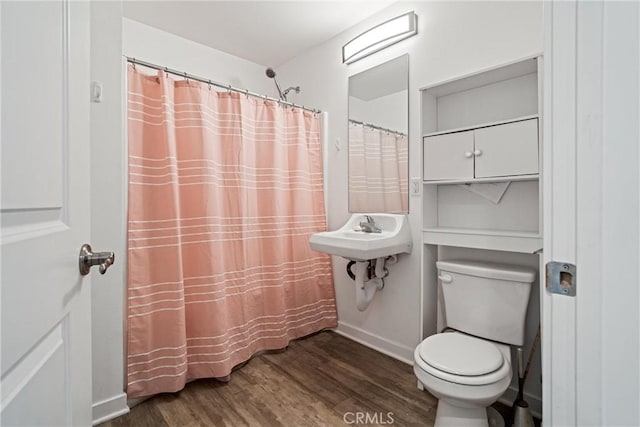 full bath with toilet, a sink, wood finished floors, and baseboards