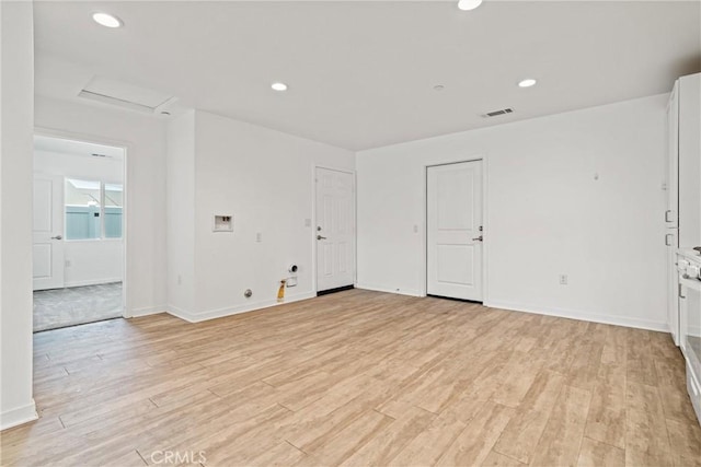 empty room with attic access, visible vents, baseboards, and light wood-style floors