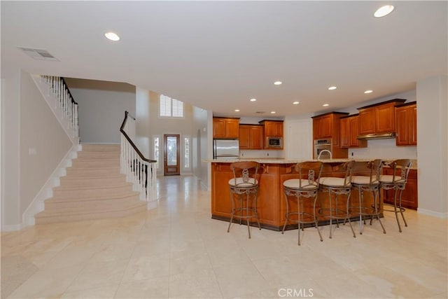 29515 Longhorn Dr, Canyon Lake, CA 92587 - kitchen with stainless steel appliances, a kitchen bar, brown cabinetry, under cabinet range hood, and recessed lighting