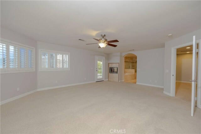 29515 Longhorn Dr, Canyon Lake, CA 92587 - unfurnished living room featuring arched walkways, light colored carpet, and a ceiling fan