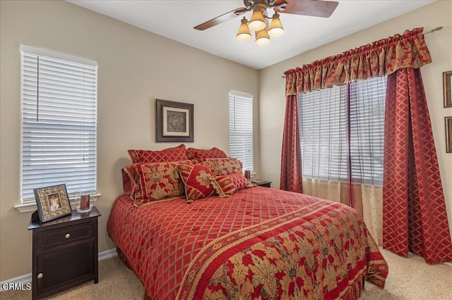 bedroom featuring light colored carpet, baseboards, and a ceiling fan