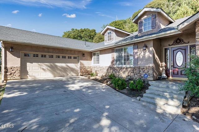 view of front facade featuring stone siding, stucco siding, an attached garage, and driveway