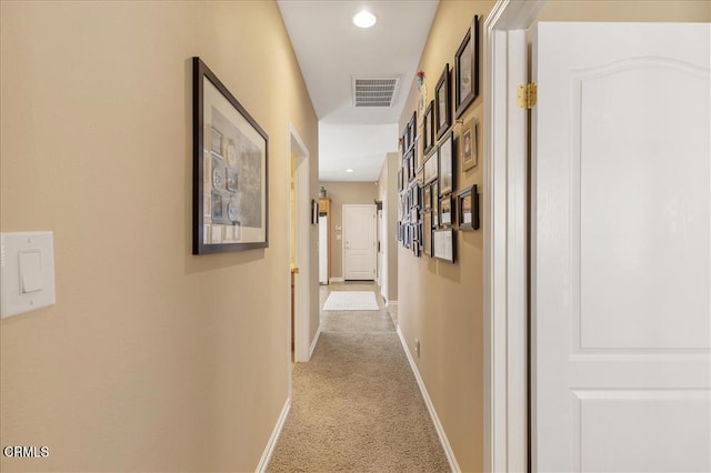 corridor with baseboards, light carpet, and visible vents