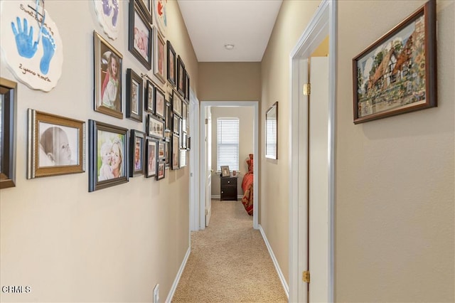 hall with light colored carpet and baseboards