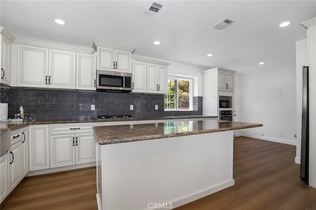 kitchen with dark wood finished floors, visible vents, stainless steel appliances, and backsplash