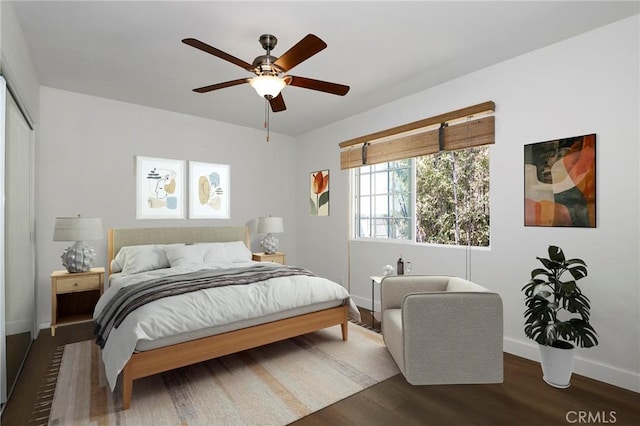 bedroom featuring baseboards, wood finished floors, a ceiling fan, and a closet