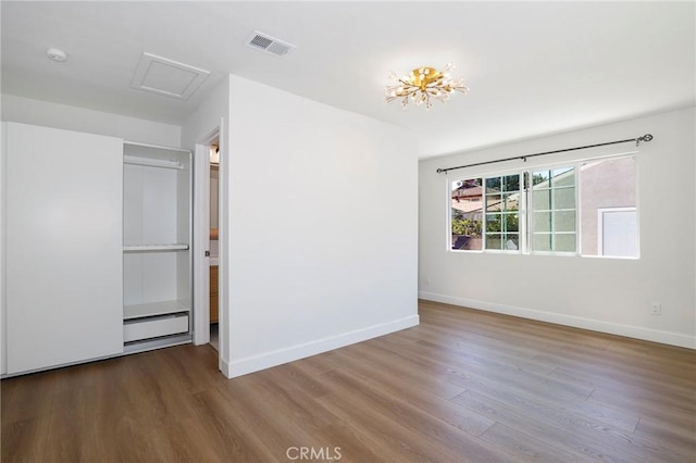 spare room with visible vents, a baseboard heating unit, baseboards, attic access, and wood finished floors