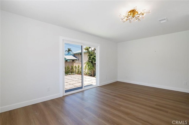 spare room with baseboards, visible vents, and wood finished floors