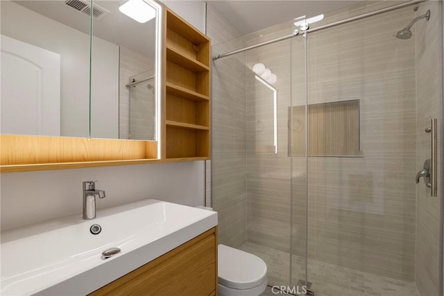 bathroom with toilet, visible vents, a shower stall, and vanity