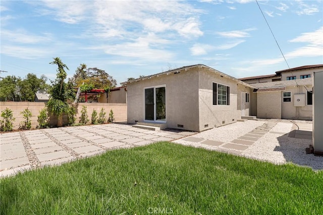 rear view of house with a patio, crawl space, a lawn, stucco siding, and fence
