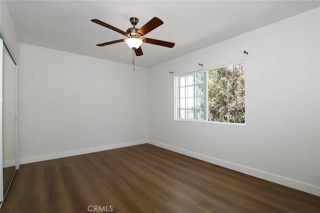 unfurnished bedroom featuring dark wood finished floors, a closet, and baseboards