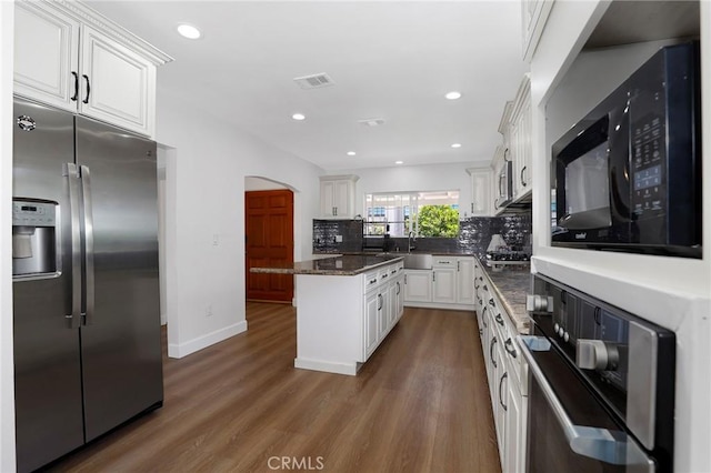kitchen featuring visible vents, arched walkways, white cabinets, appliances with stainless steel finishes, and wood finished floors