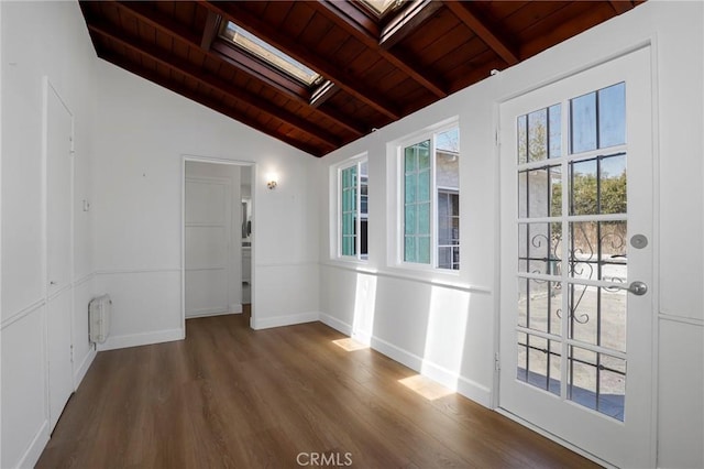 empty room featuring lofted ceiling with skylight, wood finished floors, baseboards, and wooden ceiling
