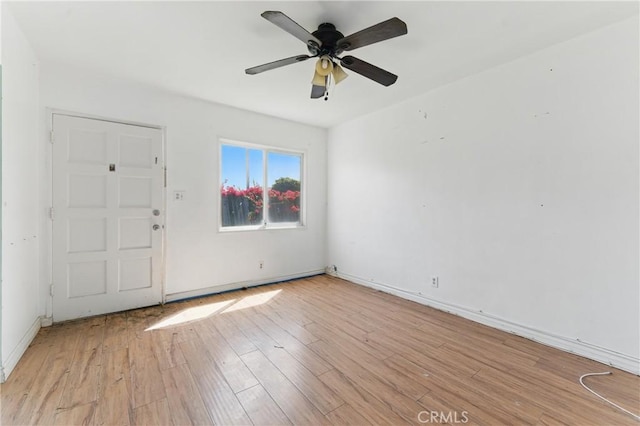 empty room featuring light wood-type flooring, a ceiling fan, and baseboards
