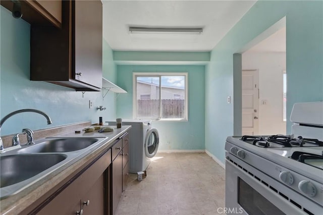 kitchen with white gas range, a sink, dark brown cabinetry, and baseboards