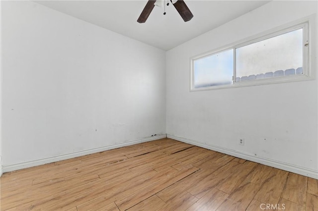 empty room with baseboards, ceiling fan, and light wood-style flooring