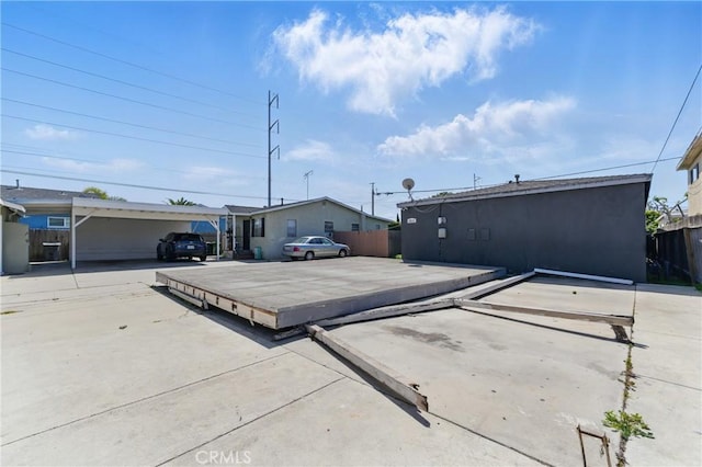exterior space featuring a deck, fence, and uncovered parking