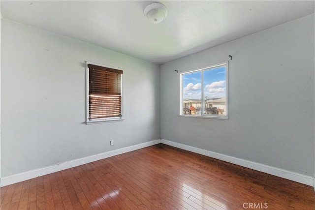 spare room featuring baseboards and hardwood / wood-style flooring