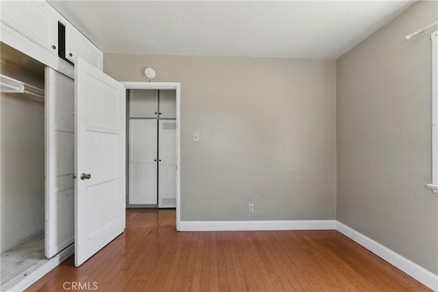 unfurnished bedroom featuring a closet, baseboards, and light wood-type flooring