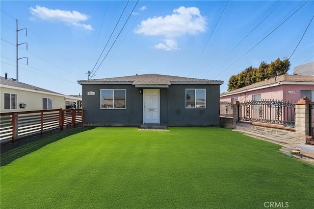 rear view of property featuring a lawn, stucco siding, and a fenced backyard