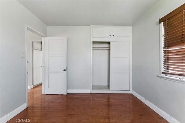 unfurnished bedroom with wood finished floors, a closet, and baseboards