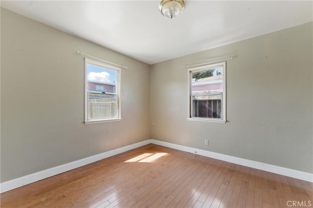 spare room with hardwood / wood-style floors and baseboards