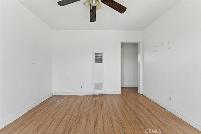 unfurnished room with a heating unit, wood finished floors, ceiling fan, and baseboards
