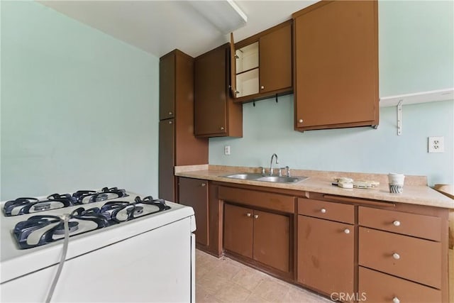 kitchen featuring white gas range oven, light countertops, and a sink