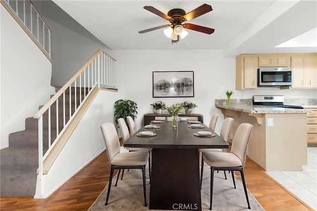 983 Elsa Ct Unit D, Corona, CA 92881 - dining room with light wood-type flooring, ceiling fan, and stairway