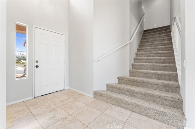 tiled foyer featuring stairs and baseboards
