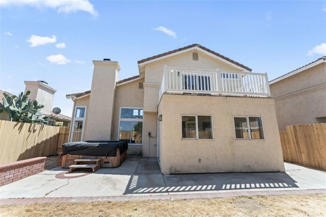 rear view of house featuring stucco siding, a fenced backyard, a patio, and a hot tub