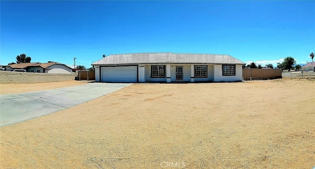 ranch-style house featuring fence, an attached garage, concrete driveway, and stucco siding
