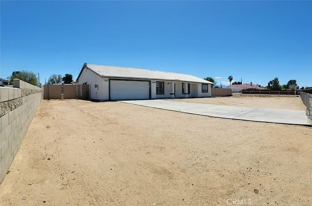 ranch-style house featuring fence, an attached garage, a tile roof, stucco siding, and concrete driveway