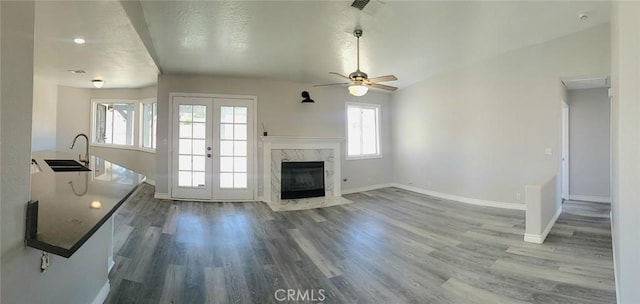unfurnished living room featuring french doors, baseboards, a sink, and wood finished floors
