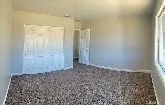 unfurnished bedroom featuring visible vents, carpet flooring, baseboards, and a closet