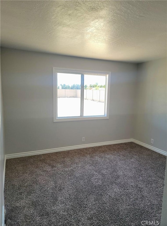 carpeted empty room with a textured ceiling and baseboards