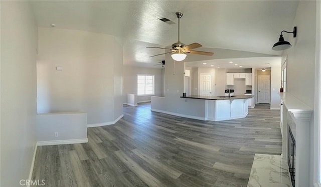 kitchen featuring visible vents, dark countertops, ceiling fan, white cabinets, and light wood-style flooring