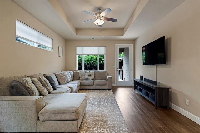 living area featuring baseboards, ceiling fan, wood finished floors, and a raised ceiling