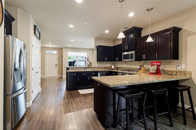 kitchen featuring appliances with stainless steel finishes, dark wood finished floors, baseboards, a peninsula, and recessed lighting