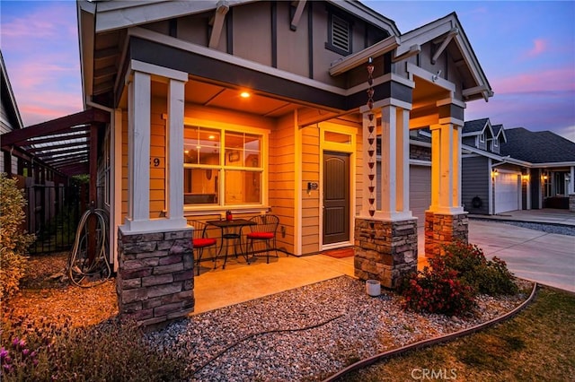 view of front of house with concrete driveway, board and batten siding, covered porch, and stone siding
