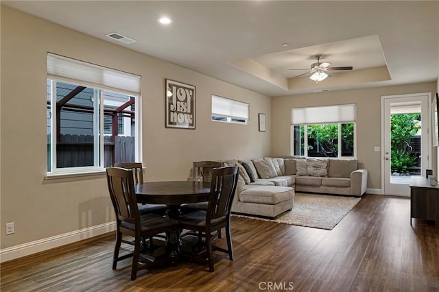 dining area featuring visible vents, a tray ceiling, ceiling fan, and dark wood-type flooring