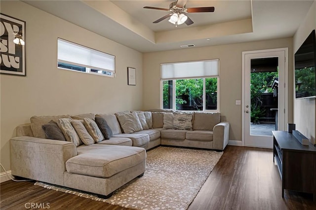 living area featuring ceiling fan, visible vents, a wealth of natural light, and a raised ceiling