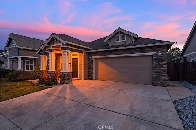 view of front of property with concrete driveway, fence, stone siding, and a garage