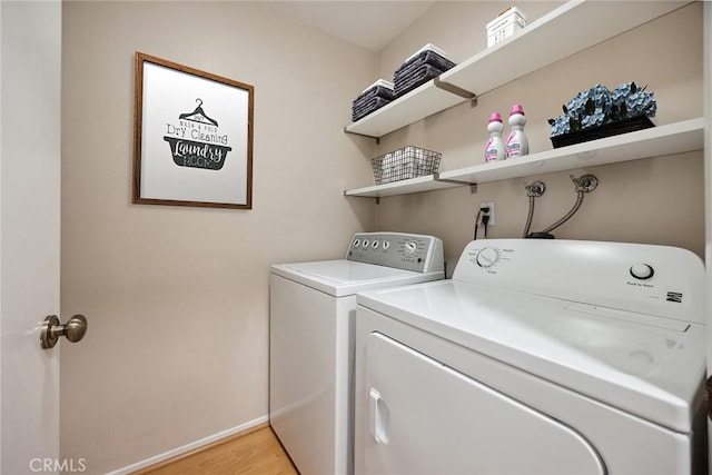 laundry area with light wood-style floors, baseboards, separate washer and dryer, and laundry area