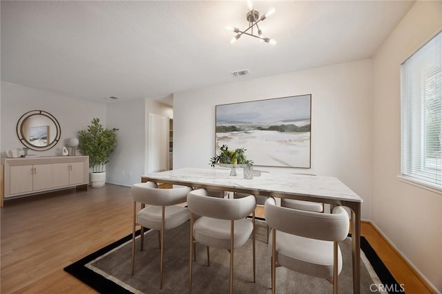 dining space featuring visible vents, baseboards, a notable chandelier, and light wood-style floors