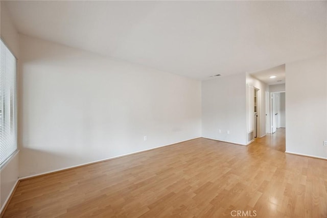 spare room with baseboards and light wood-type flooring