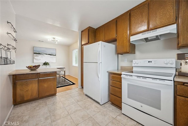 kitchen featuring white appliances, brown cabinetry, and under cabinet range hood
