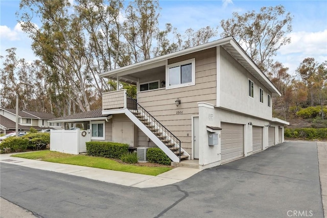 multi unit property with stairs, a garage, and aphalt driveway