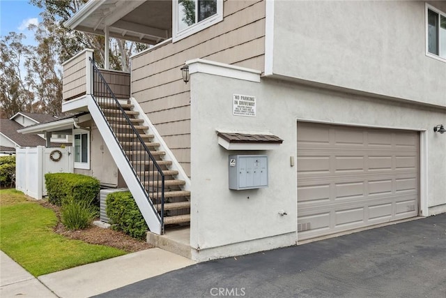 view of home's exterior with driveway, stairway, stucco siding, and a garage