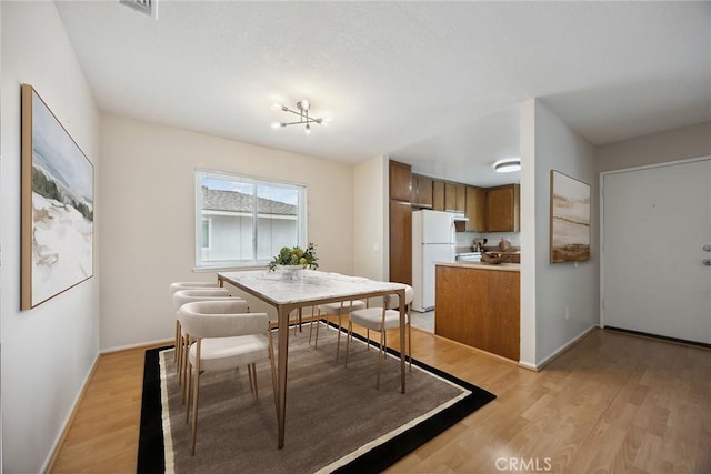 dining space with visible vents, light wood-style flooring, and baseboards